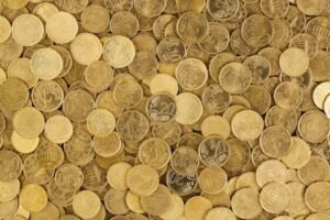 A close-up shot of Euro coins scattered in a pile, showcasing a rich golden texture.