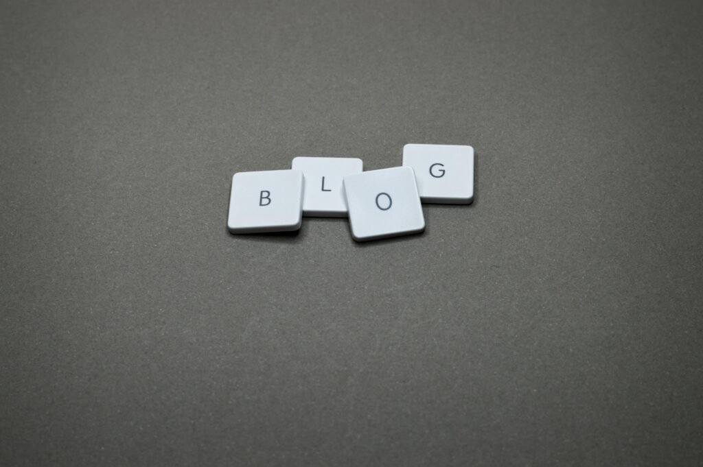 White Scrabble tiles spelling 'Blog' against a minimalist gray background.